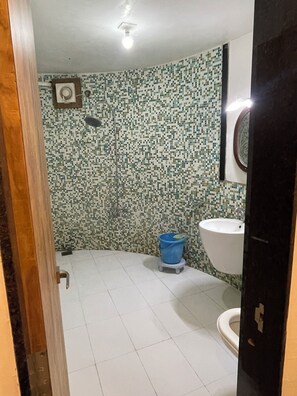 A bathroom with a tiled floor, a toilet, a sink, and a shower. - Hotel Shyam Farm House and Resort (Talala)