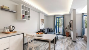 Una sala de estar moderna con sofá, mesa de comedor, cocina y un ventanal grande.