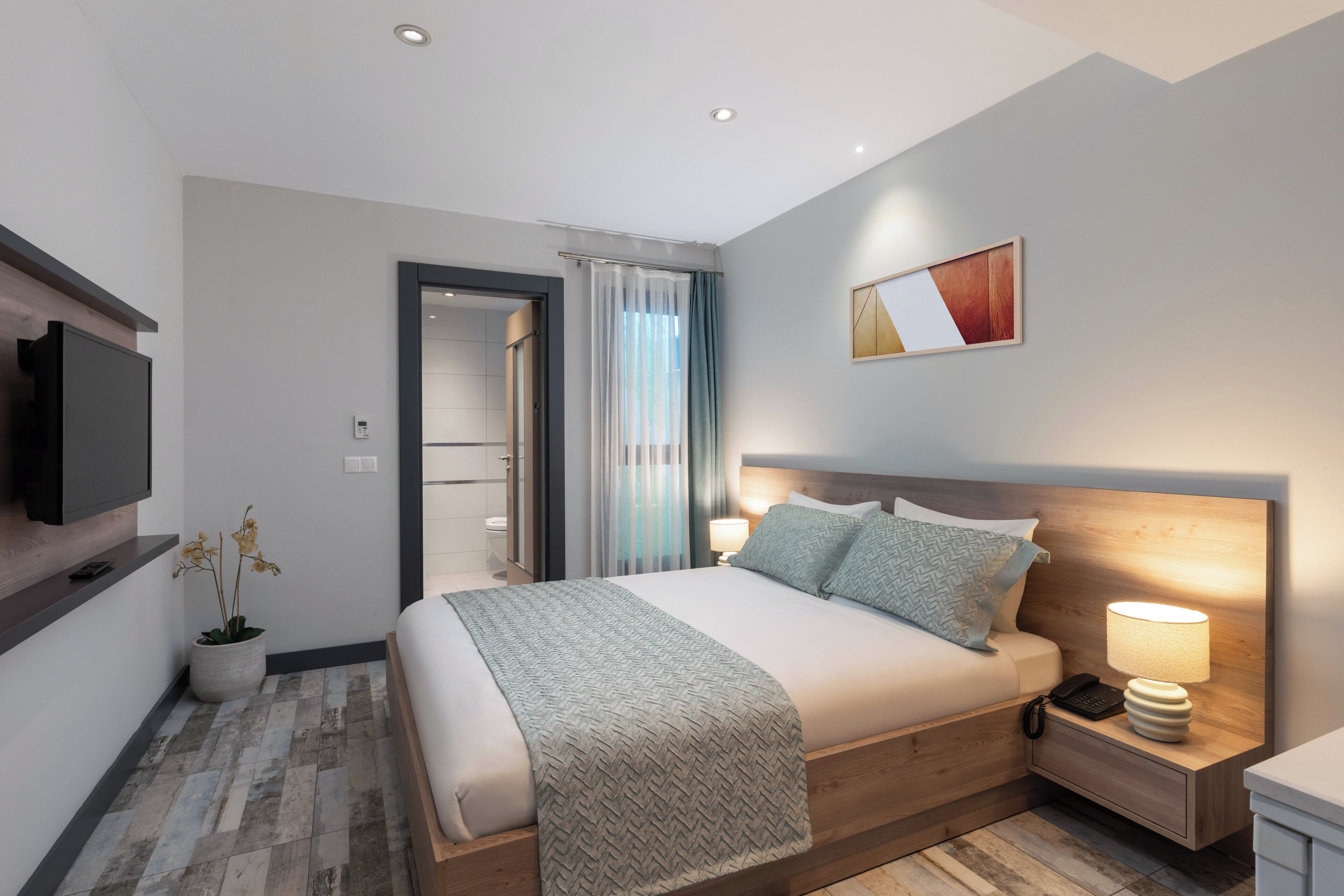 Una habitación de hotel moderna con cama, mesita de noche, lámpara, televisor y una planta en maceta.