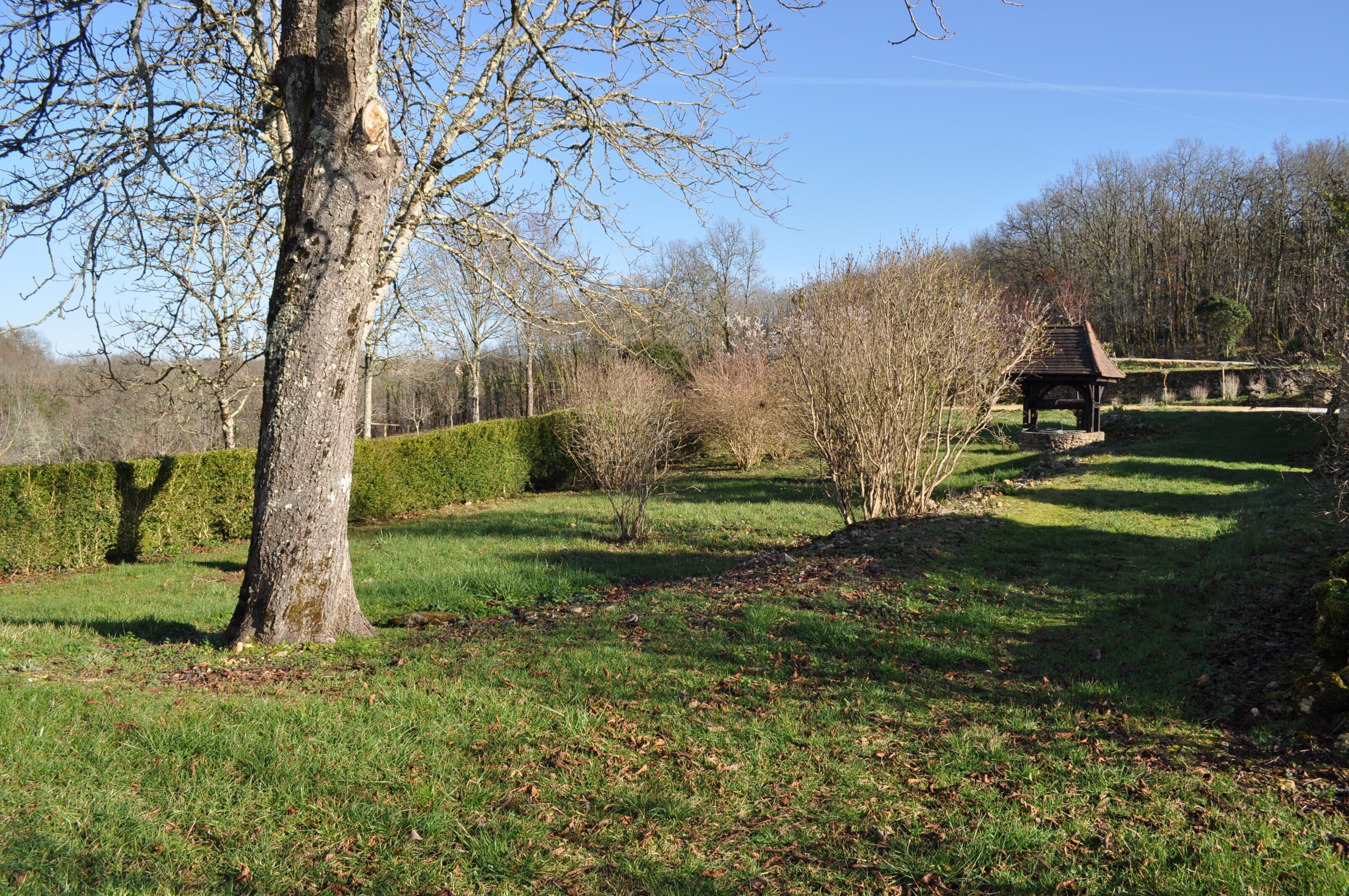 A park with a well-maintained lawn, a wooden gazebo, and a large tree.