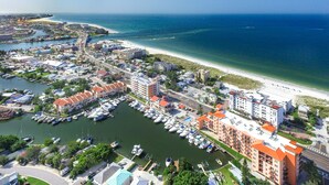 Vista aérea de un pueblo costero con un puerto deportivo, playa y diversos edificios.