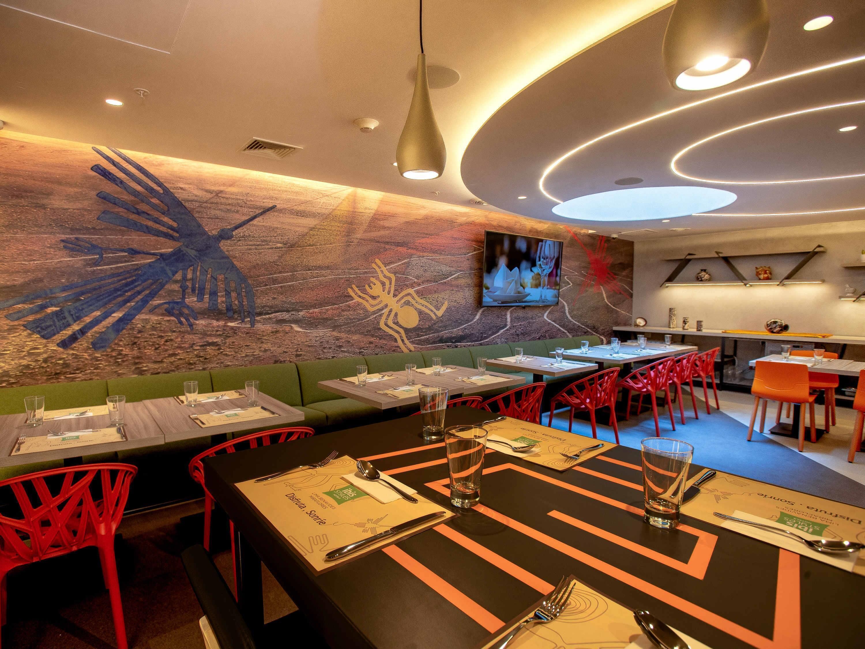 Un restaurante con cabinas, sillas rojas y un mural en la pared.
