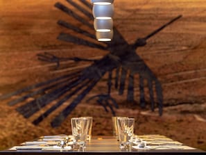 Une table mise avec des verres et des couverts, et une grande œuvre d’art abstraite accrochée au mur en arrière-plan.