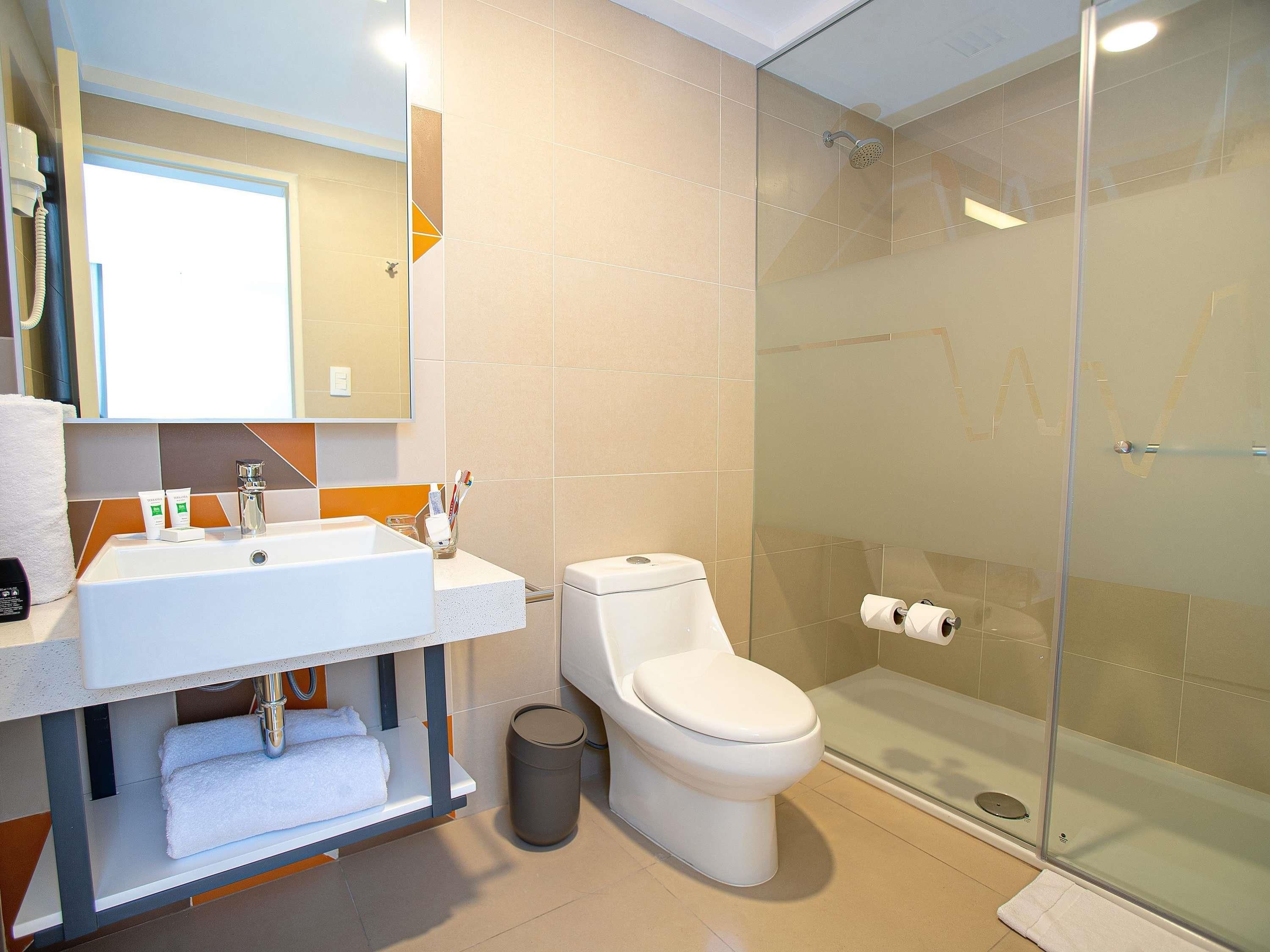 A modern bathroom with a glass-enclosed shower, a white sink, and a toilet.