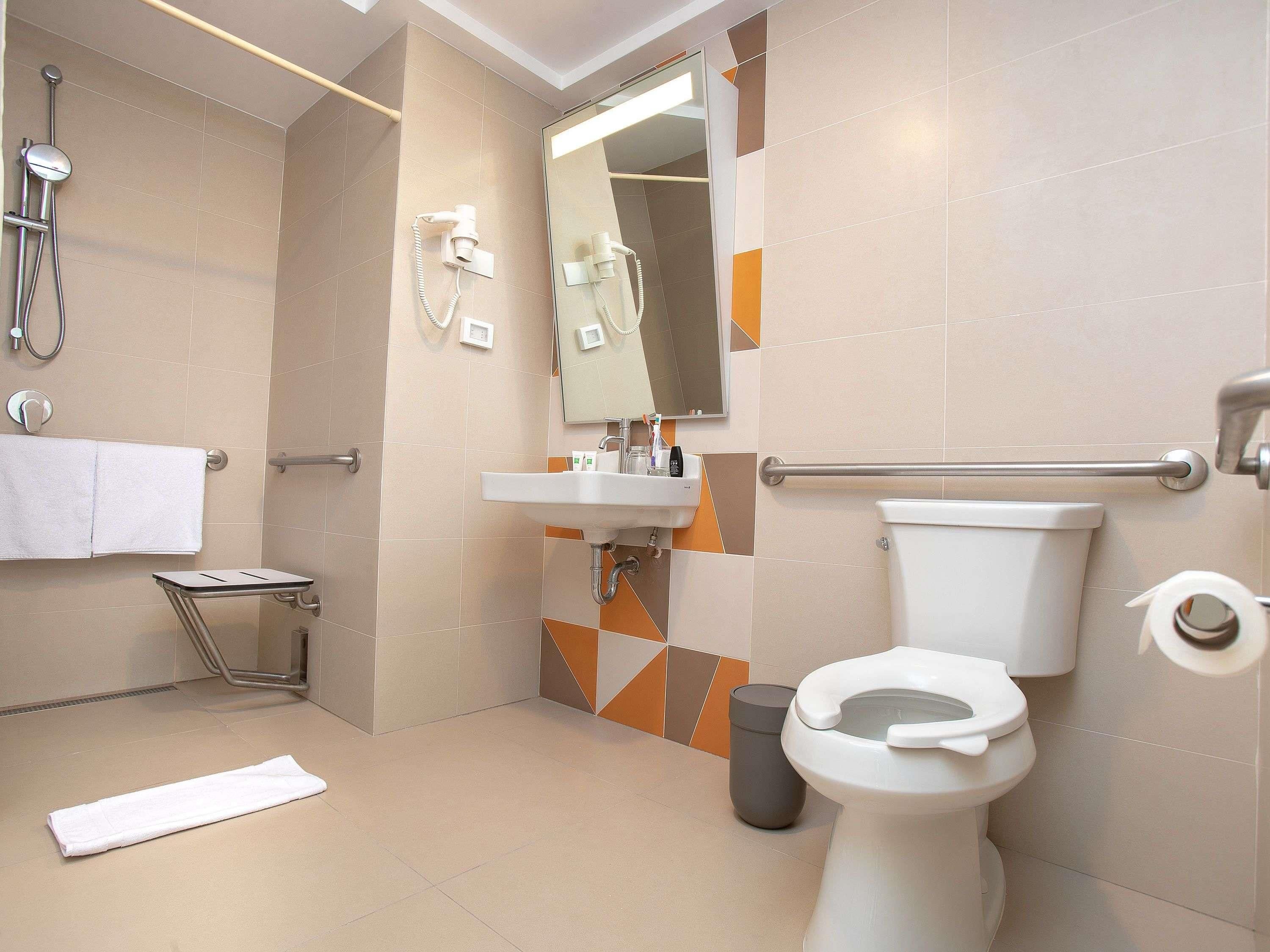Un baño moderno con ducha, inodoro, lavamanos y secamanos.
