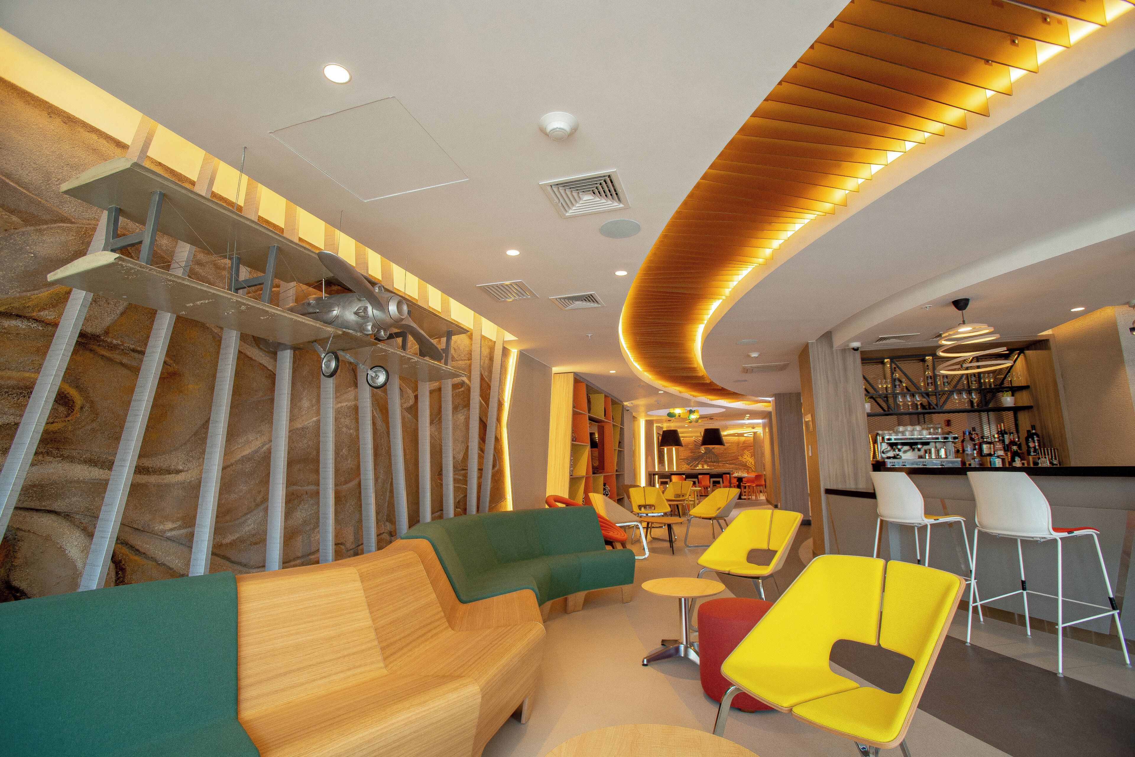 A modern interior with a curved wooden ceiling, a bar area, and colorful seating.