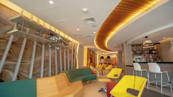A modern interior with a curved wooden ceiling, a bar area, and colorful seating.