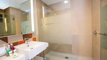 A modern bathroom with a glass shower enclosure, a white sink, and a mirror above it.