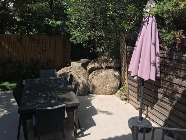 An outdoor patio with a table and chairs, a wooden fence, and a pergola with a purple canopy. - C mini villa 4/6 pers in residence with swimming pool (porto vecchio)