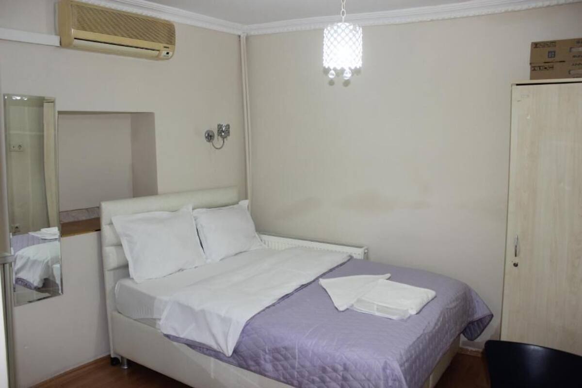 A bedroom with a bed, a mirror, a wardrobe, and a ceiling fan.