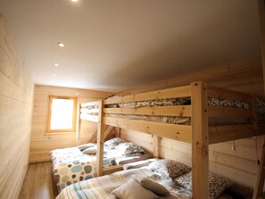 Eine Holzhütte mit Stockbetten, einem Fenster und Holzboden.