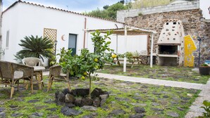 A courtyard with stone flooring, wicker furniture, a small tree with lemons, and a stone oven. - Bed And Breakfast Villa Bianca (Orosei)