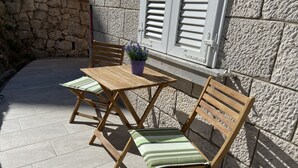 Eine Terrasse mit einem Holztisch und -stühlen, einem Blumentopf und einer Steinmauer.
