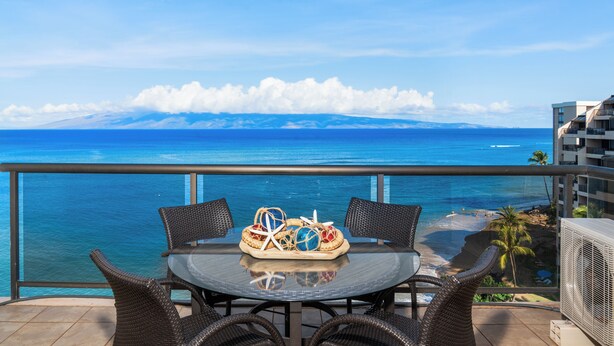 A balcony with a table and chairs overlooking a beach and ocean. - Stunning, Oceanfront Deluxe Penthouse with Island Views - Sands of Kahana 282 (Lahaina)
