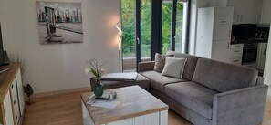 Ein modernes Wohnzimmer mit einem grauen Sofa, einem Holztisch und einem Gemälde an der Wand.