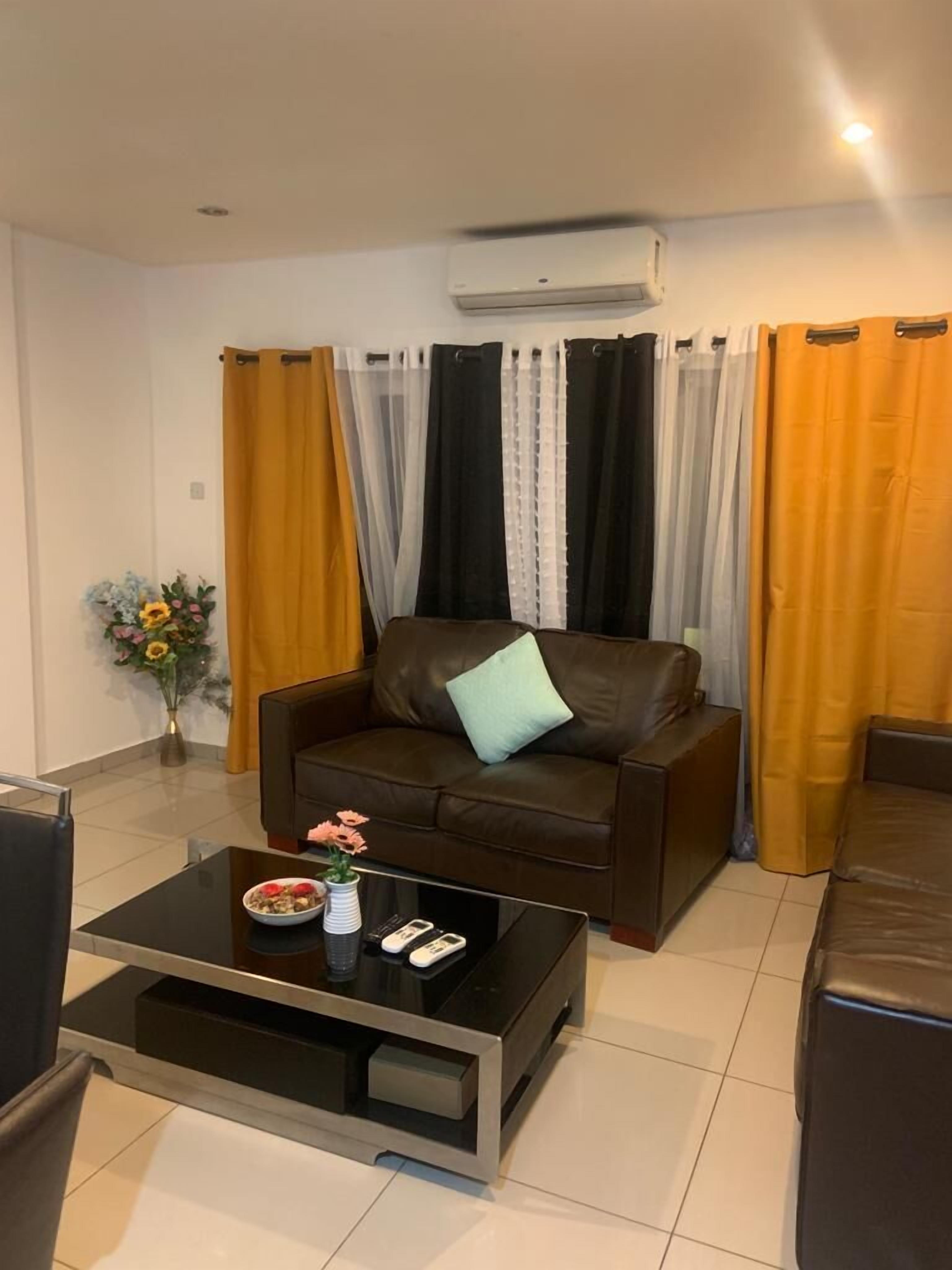 A modern living room with a brown leather sofa, a glass coffee table, and a vase of flowers.