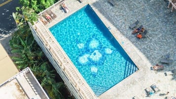 Relax by the pool surrounded by lush greenery and comfortable lounge chairs.