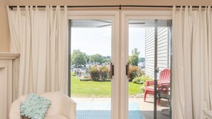 Una habitación con puerta de vidrio corredera que da a un patio con una silla roja y un tapete azul.