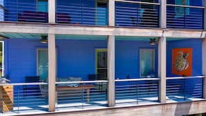 Un immeuble à plusieurs étages doté d’un balcon, d’un espace extérieur aménagé pour s’asseoir et d’une grande fenêtre.