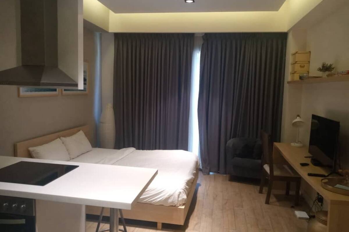 A hotel room with a bed, a desk, a TV, and a kitchenette.