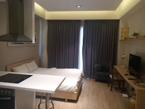 Ein Hotelzimmer mit Bett, Schreibtisch, Fernseher und einer Küchenzeile.