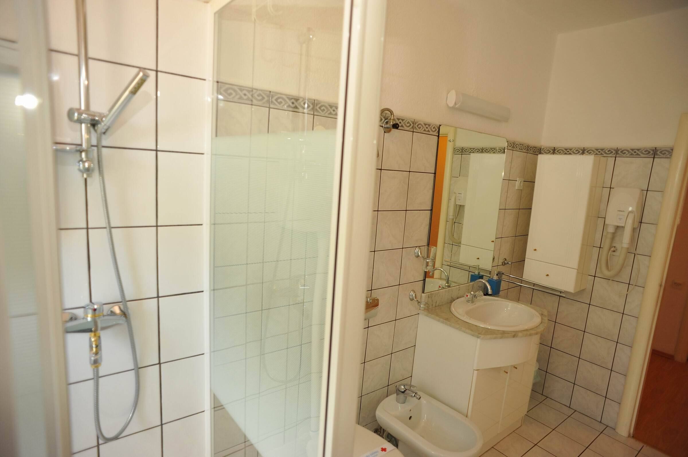 Et badeværelse med bruser, toilet, vask og spejl.