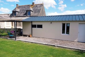 A single-story building with a metal roof, a covered patio area, and a small garden.