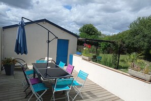 A patio with a table and chairs, a blue umbrella, and a building with a blue door.