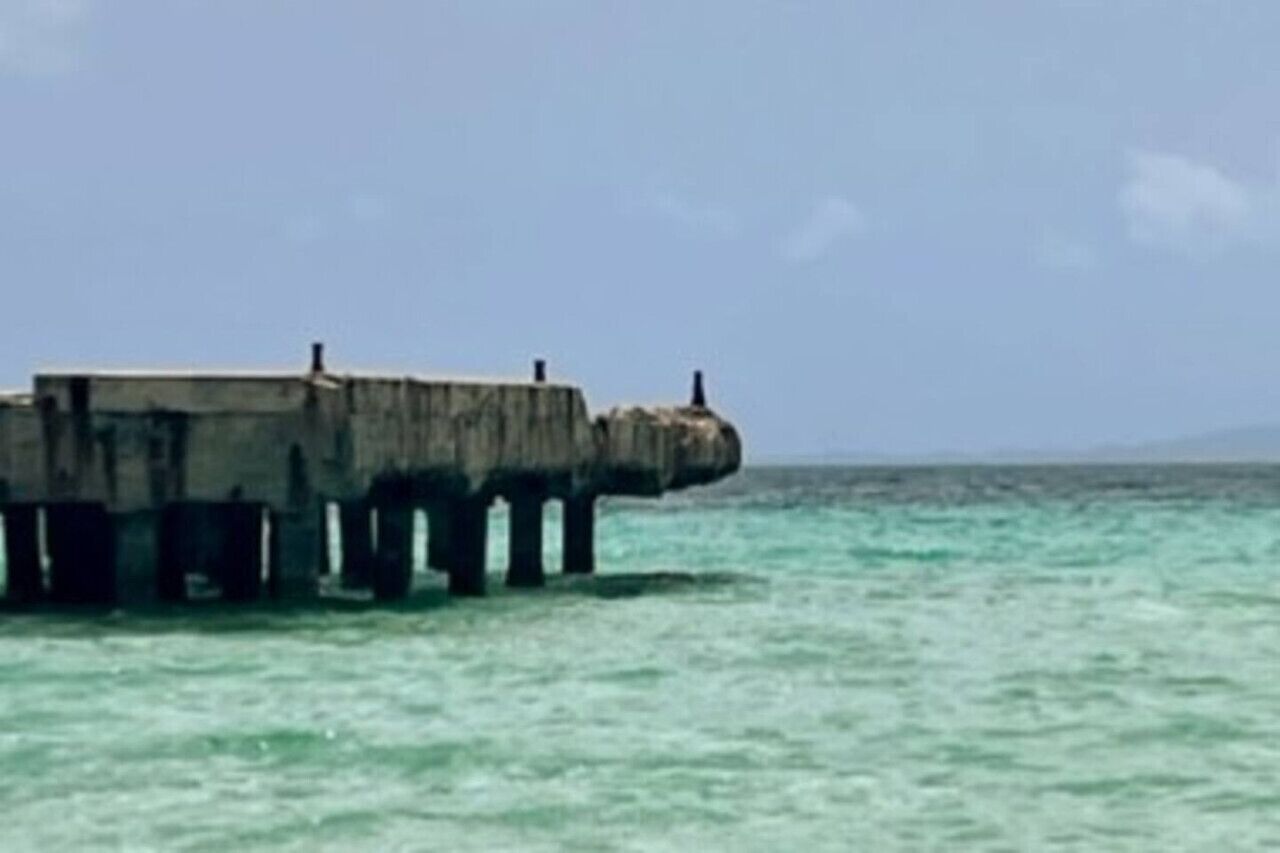 Un pilier de béton s’étendant dans la mer, avec un ciel dégagé au-dessus.