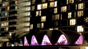 Een hotel met een modern ontwerp, met een opvallende gebogen structuur en paarse verlichting.