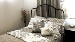Een net opgemaakt bed met beddengoed met een patroon en een zwart metalen hoofdbord.