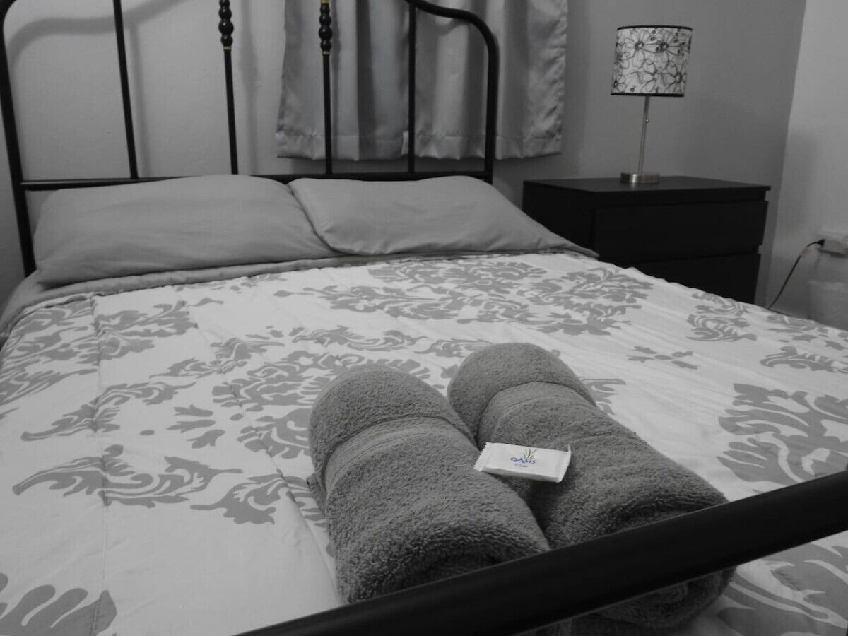 Una cama con una colcha de estampado floral y dos toallas enrolladas encima.