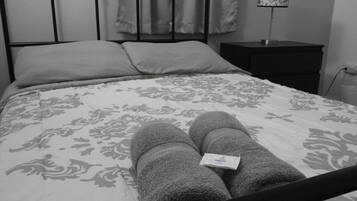 Una cama con una colcha de estampado floral y dos toallas enrolladas encima.