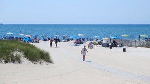 Une plage où l’on voit des gens se promener, des parasols et des chaises de plage.