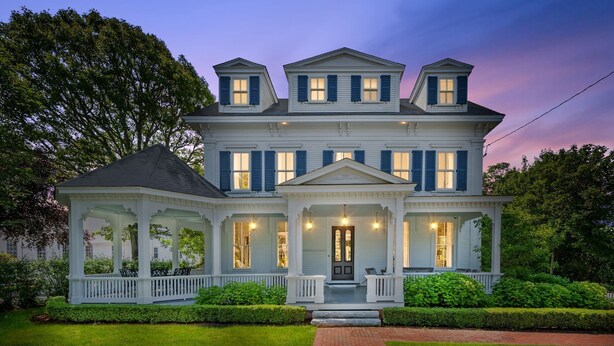 Une grande maison à deux étages, dotée d’un porche qui fait le tour de la maison et d’une entrée principale.