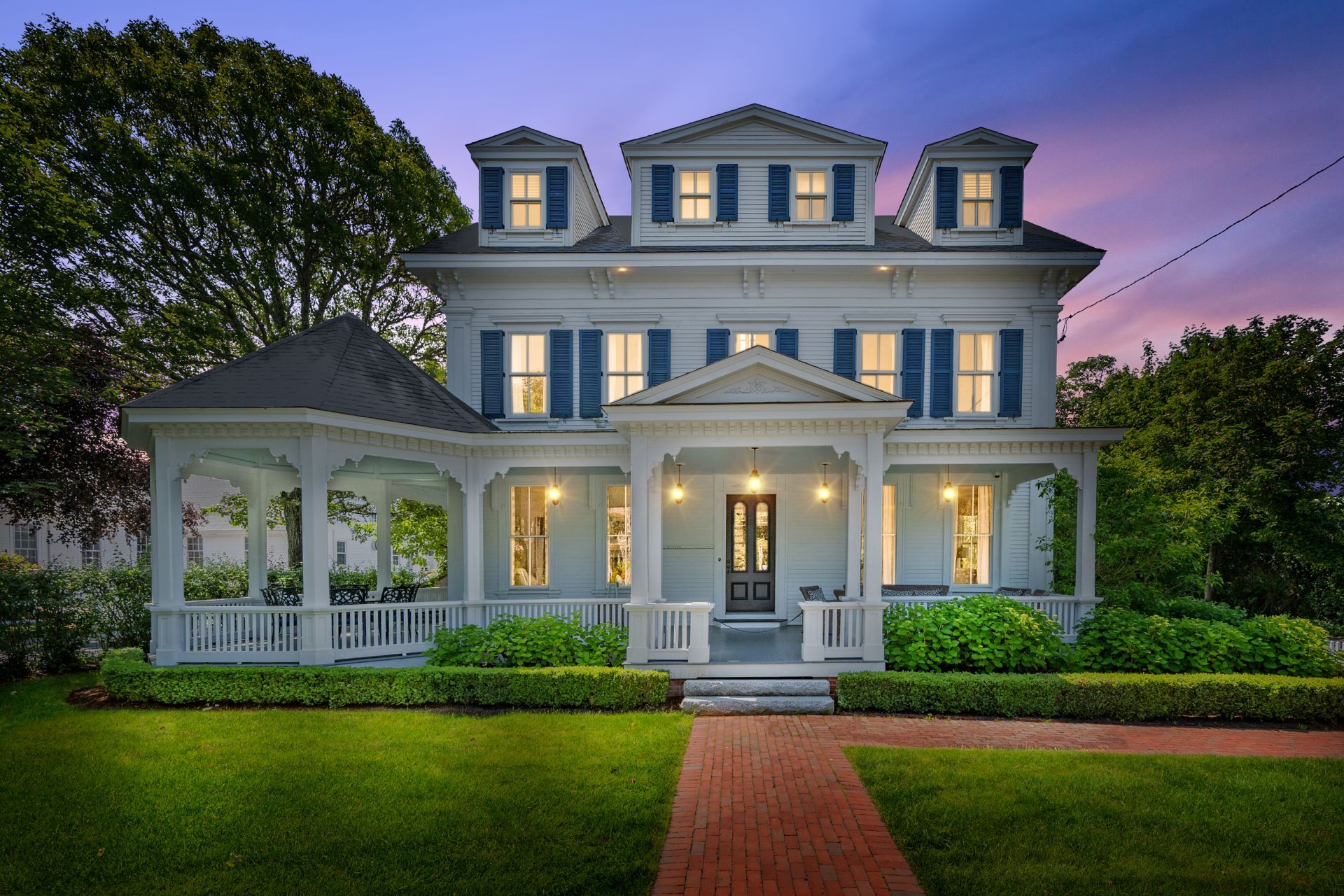 A large, two-story house with a wrap-around porch and a front entrance.