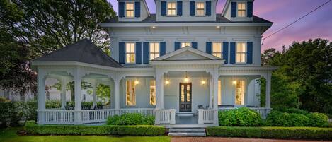 A large, two-story house with a wrap-around porch and a front entrance.