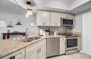 A modern kitchen with granite countertops, stainless steel appliances, and light-colored cabinetry.