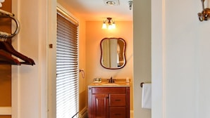 Un bagno con un mobile vanitario in legno, uno specchio e un asciugamano appeso al muro.