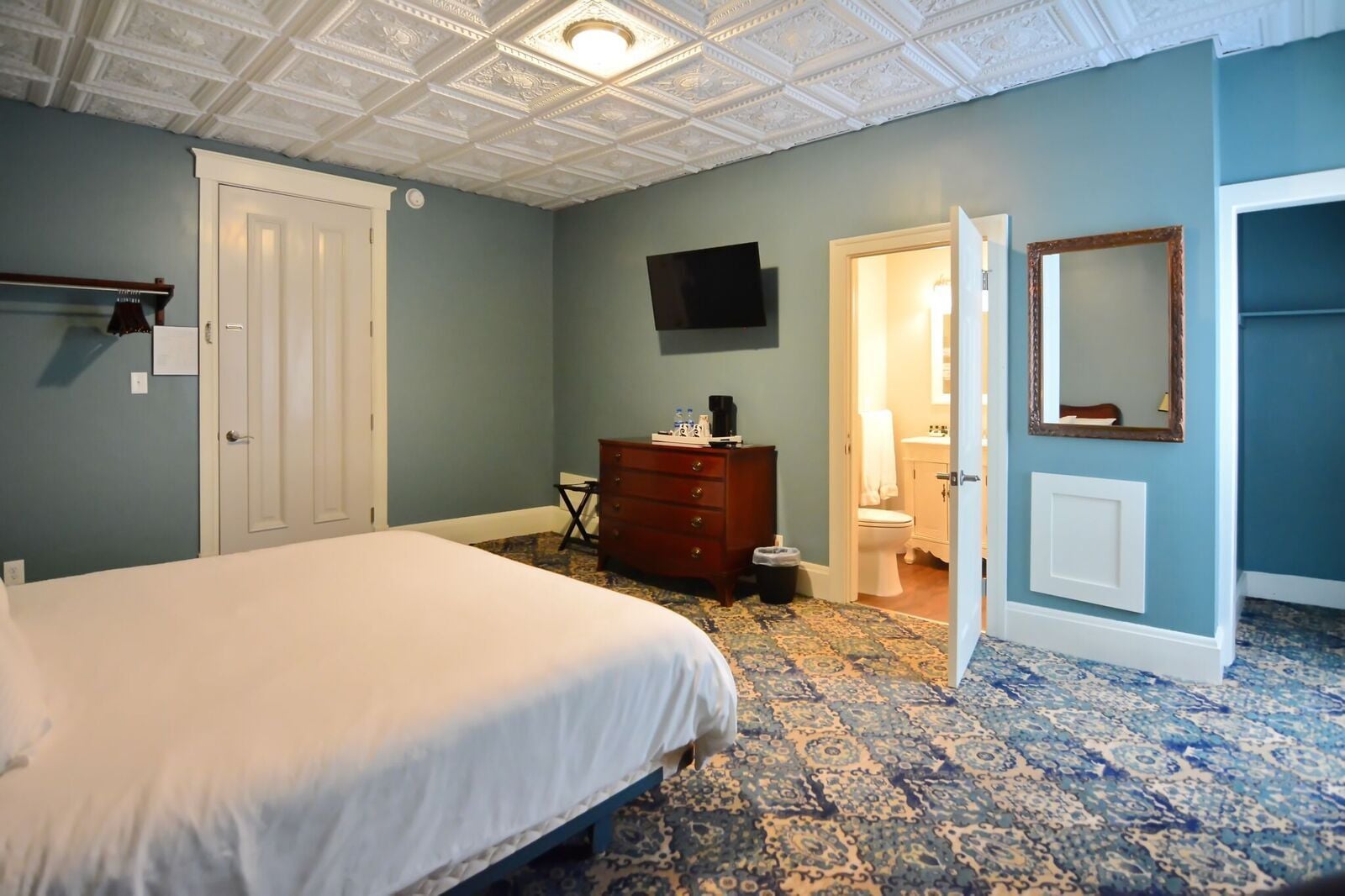 A bedroom with a bed, dresser, and a television on the wall.