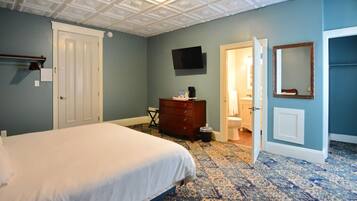 A bedroom with a bed, dresser, and a television on the wall.