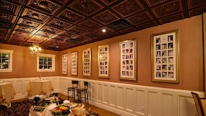 Una sala da banchetto con soffitto alto, pannelli in legno decorati e fotografie incorniciate alle pareti.