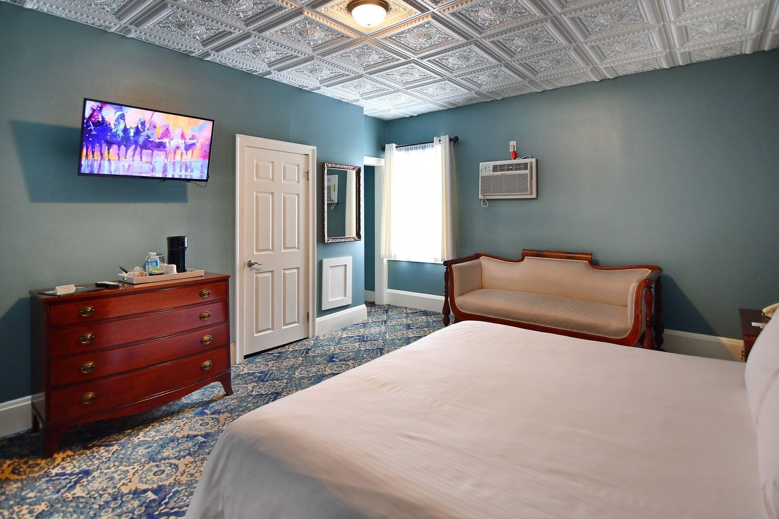 Un dormitorio con una cama grande, un aparador, un televisor y un techo con diseños elaborados.