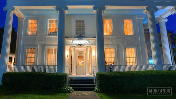 L'esterno dell'Avon Inn, caratterizzato da un'imponente ingresso con colonne, una facciata ben illuminata e un portico accogliente.