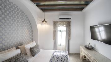 Un dormitorio con cama, pared con diseño, televisor y consola decorativa.