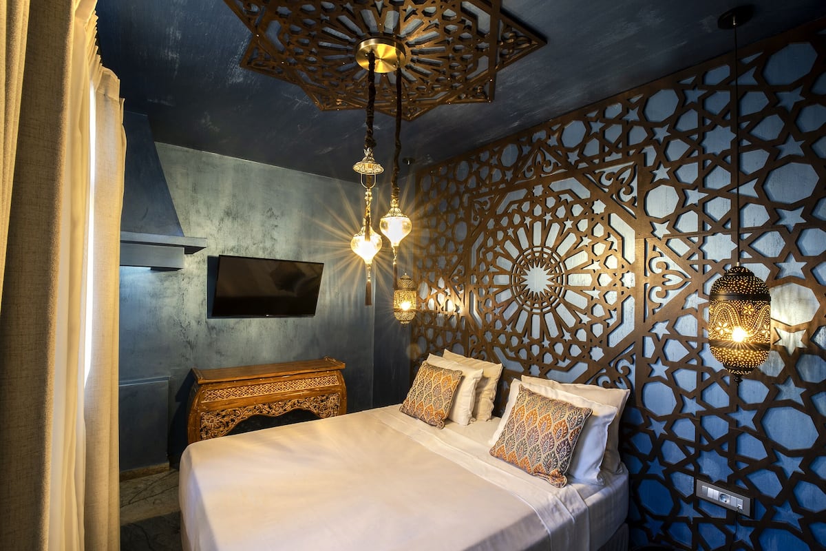 Een moderne slaapkamer met een bed, decoratieve wandpanelen en hanglampen.