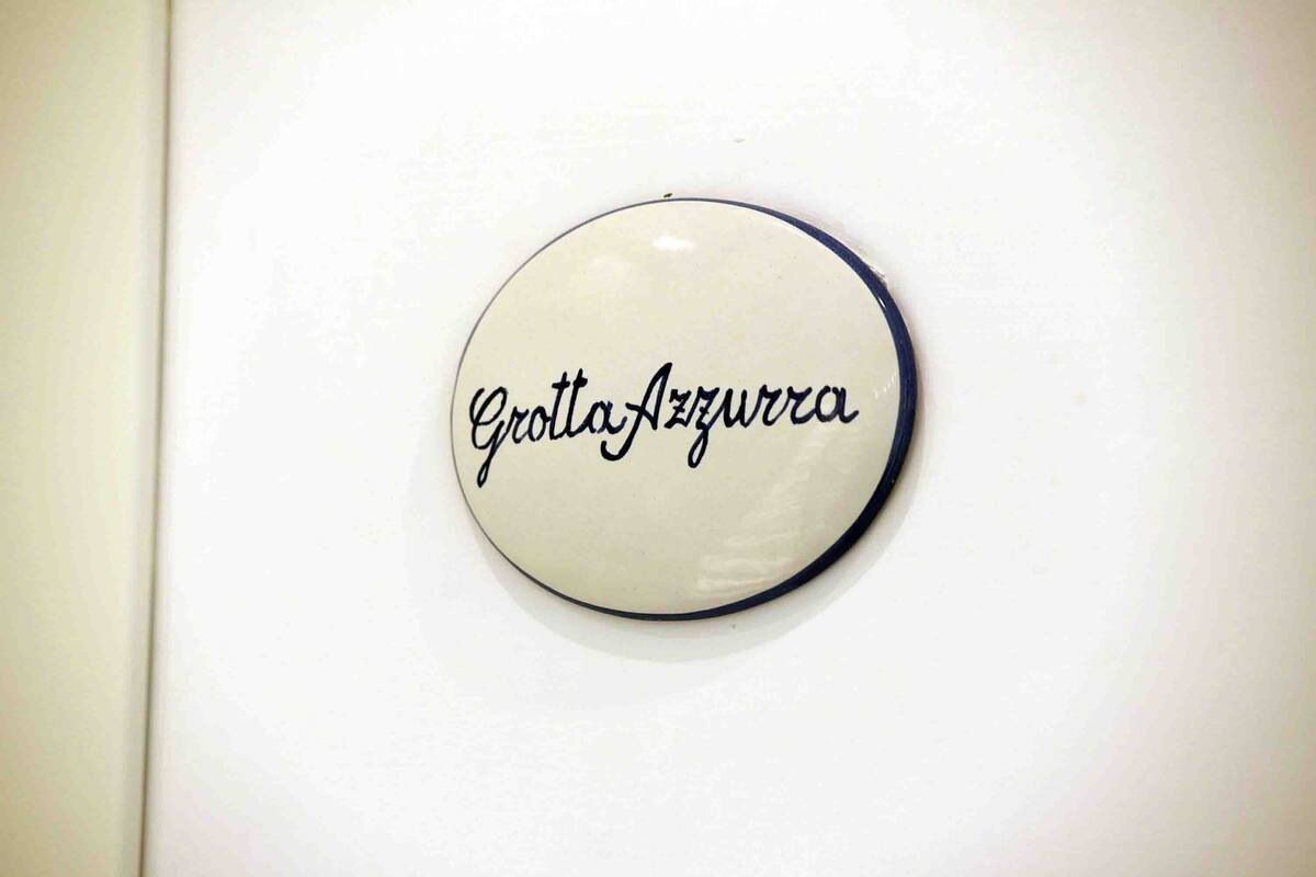 Un panneau rond et blanc, avec des lettres noires, sur lequel on peut lire : « Grotte Azurra ».