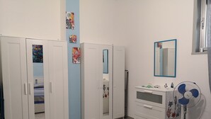 Un dormitorio con cama, cómoda, espejo y ventilador.