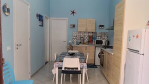 Una cocina compacta con mesa, sillas, lavadora y refrigerador.