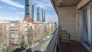 Een balkon met uitzicht op moderne wolkenkrabbers, een bakstenen muur en een heldere lucht.
